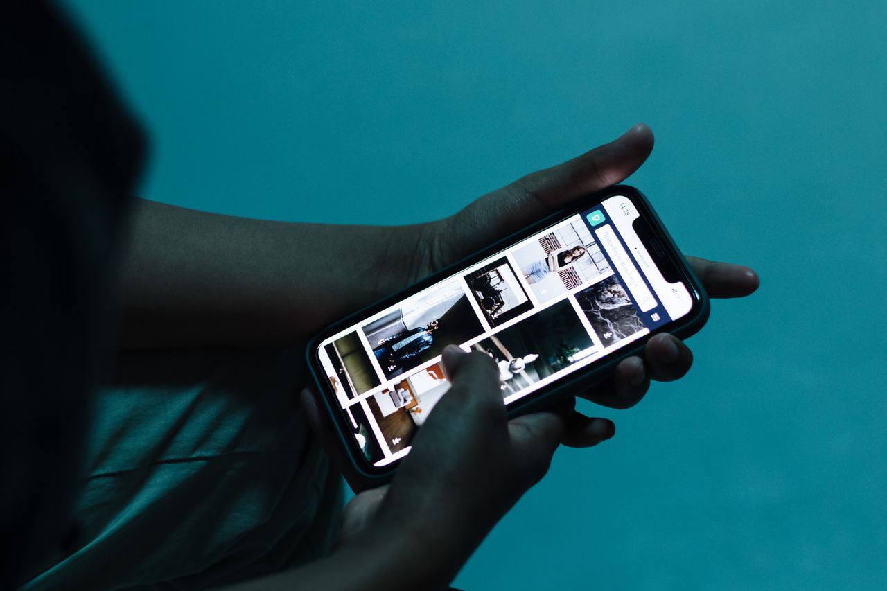 Person scrolling through a phone in dim light